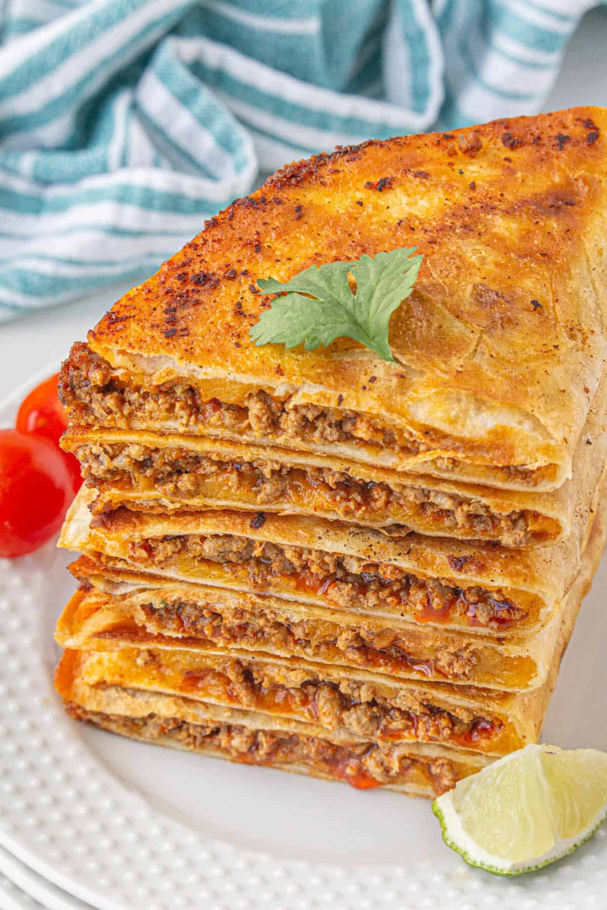 Cheesy ground beef quesadillas stacked up on a plate.