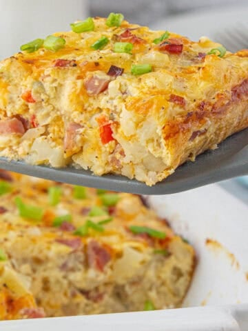 Ham and Hashbrown breakfast casserole in a baking dish with a slice on a spatula.