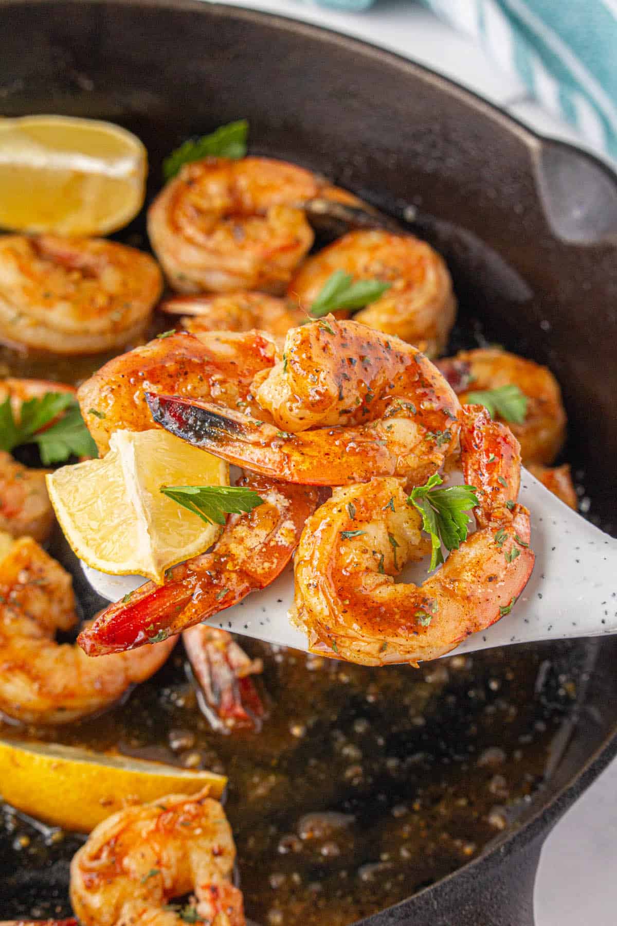 Honey butter Old Bay fried shrimp in a skillet, with a spatula scooping out some shrimp.