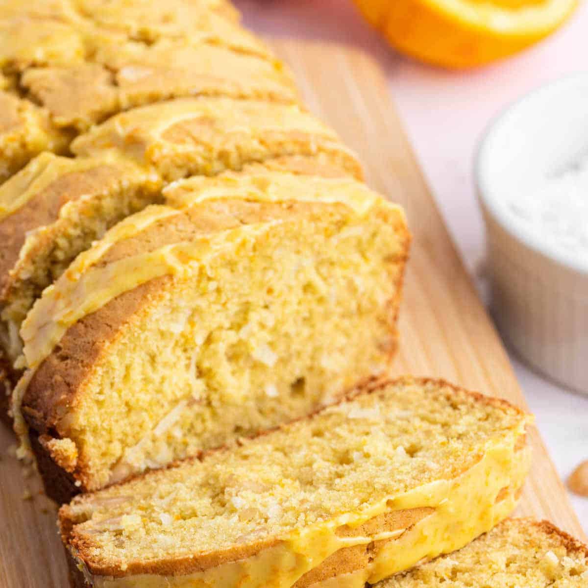 A loaf of Macadamia coconut bread sliced on a cutting board.