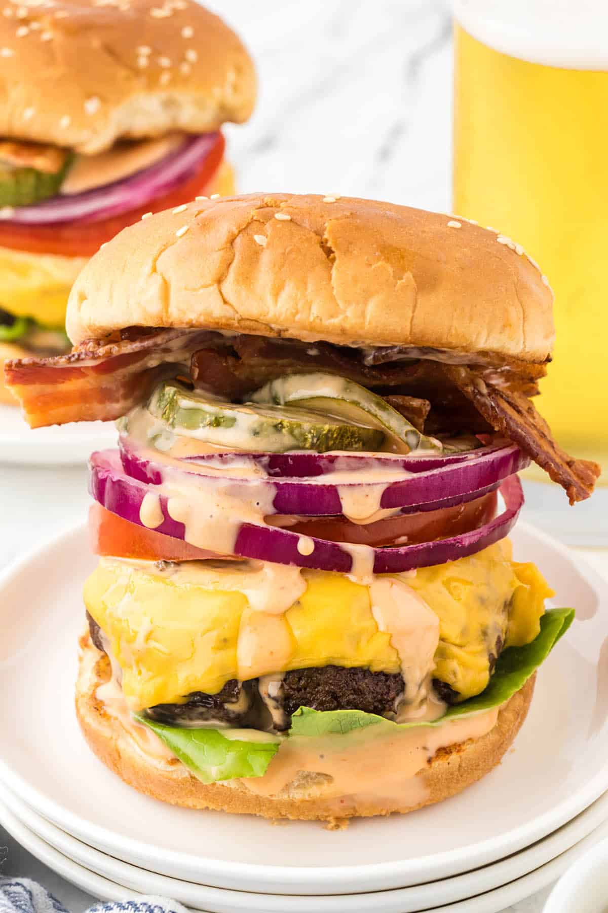 Loaded steakhouse cheeseburgers on a plate dripping with sauce.