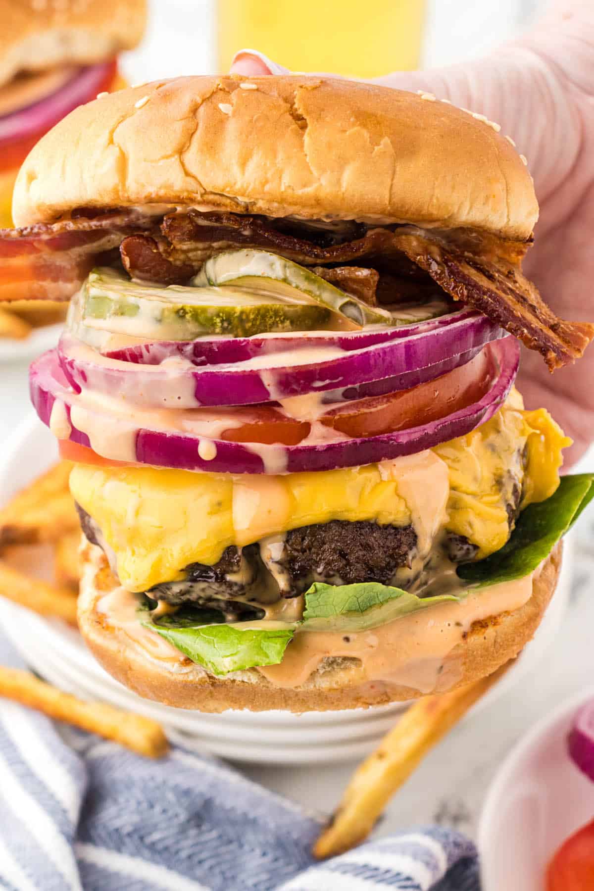 A loaded steakhouse burger topped with bacon, cheese, tomatoes, onions lettuce and sauce.