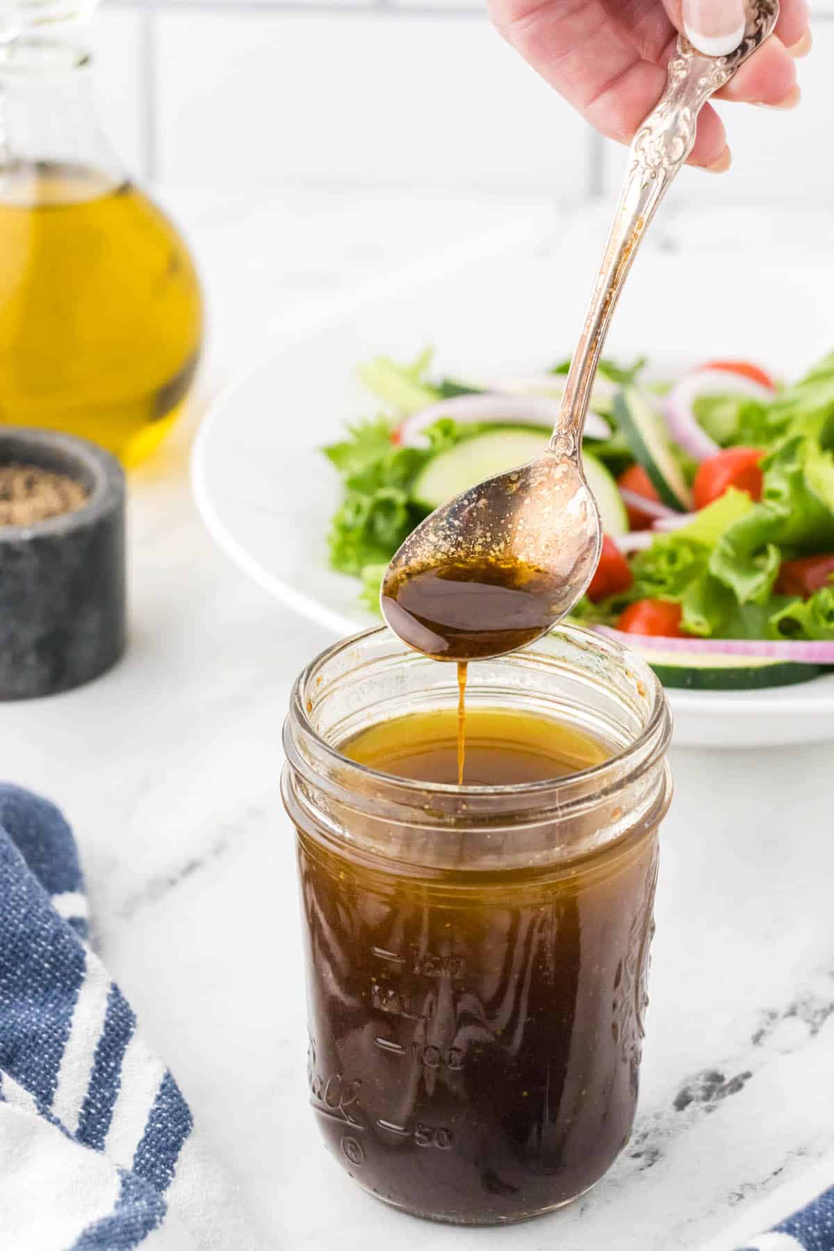 Sweet Balsamic Vinegar Dressing in a small jar, with a spoon stirring it.