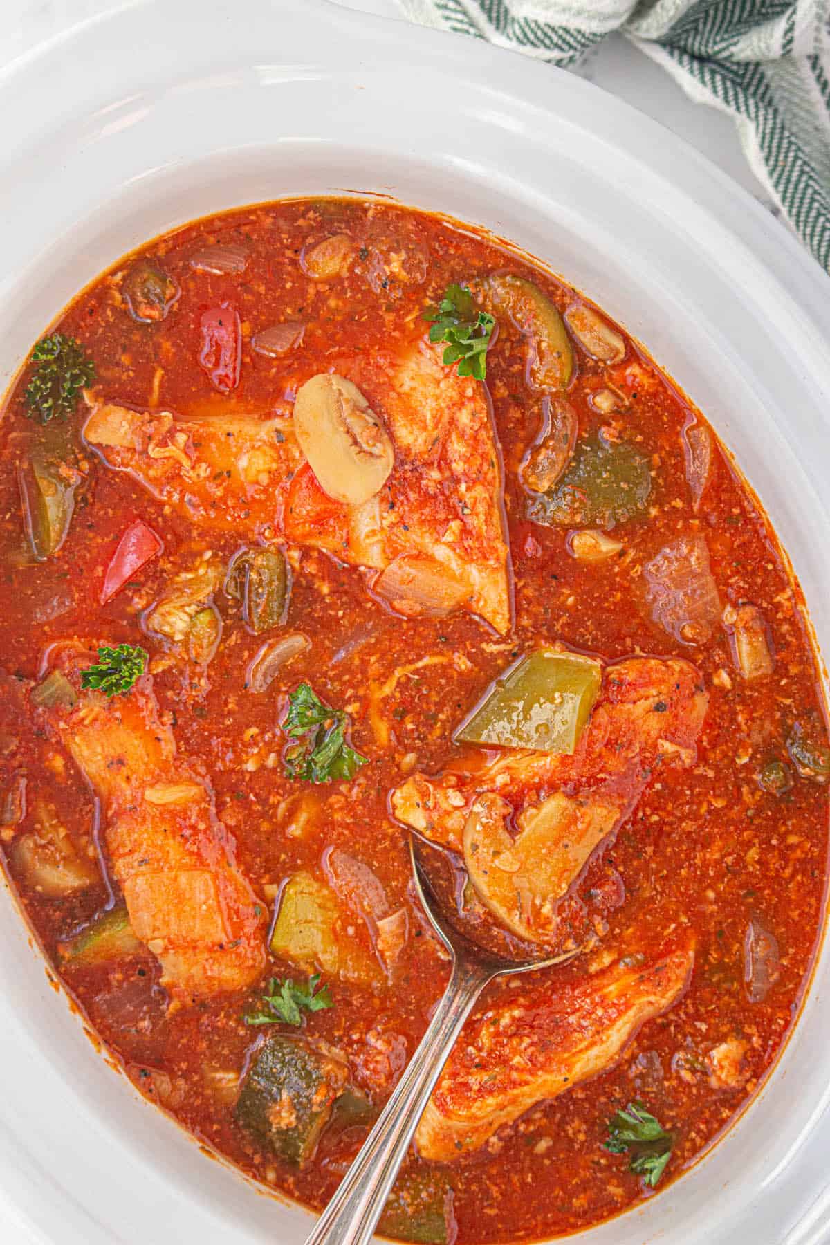 Crockpot Chicken Cacciatore in a slow cooker with a serving spoon.