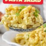 Deviled Egg Pasta Salad in a bowl with a serving spoon taking a big scoop. With print overlay for clarification.