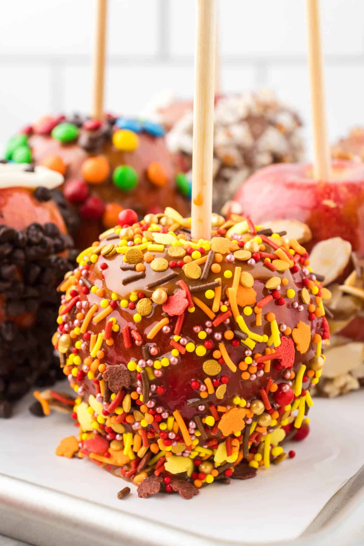 Gourmet caramel apples sitting on parchment paper.