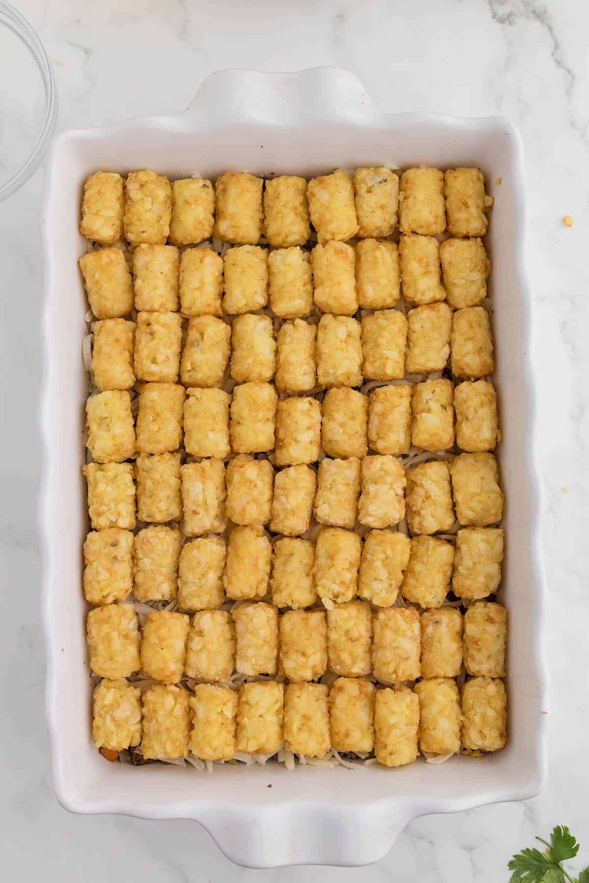 Tater tot bake in a baking dish, ready to go into the oven to be baked.