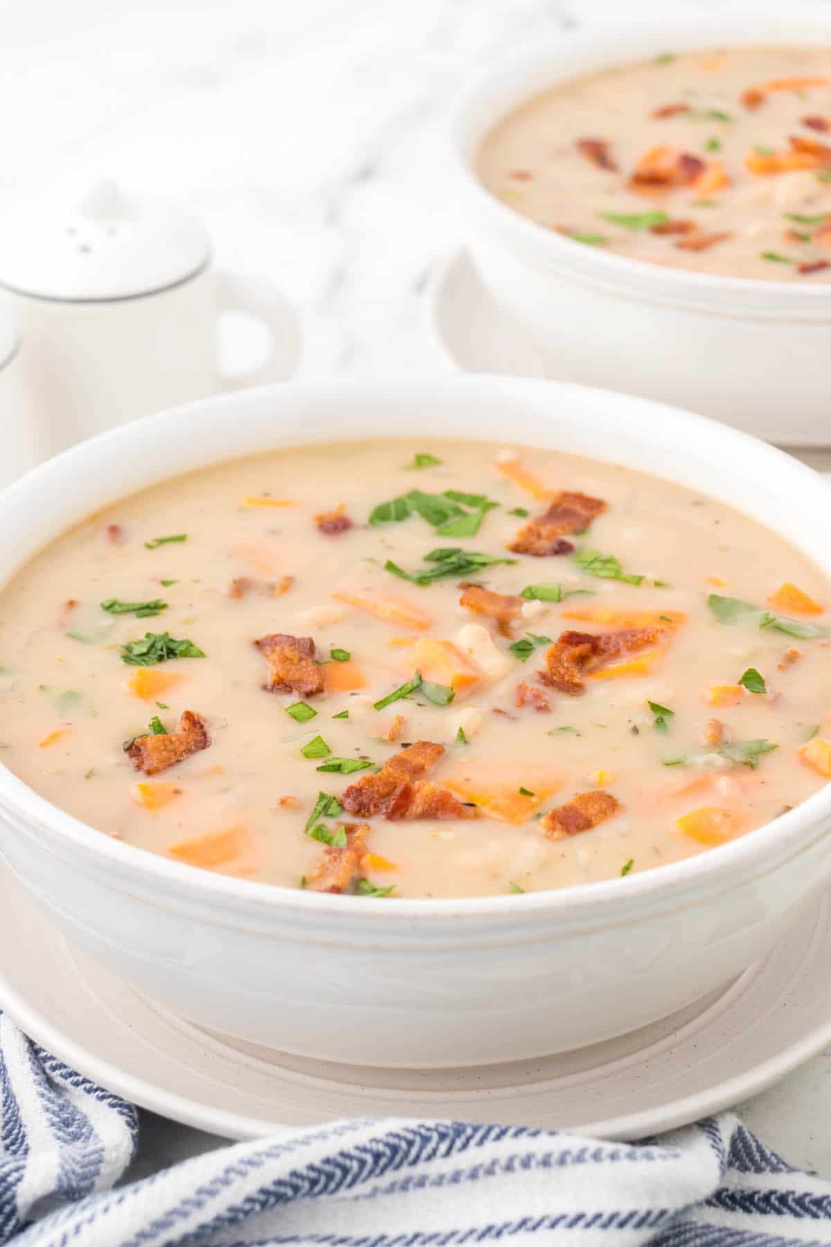 Two white bowls filled with bean with bacon soup.