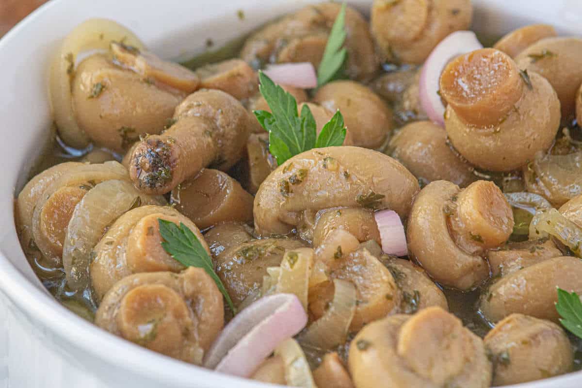 A bowl filled with pickled mushrooms and shallots.