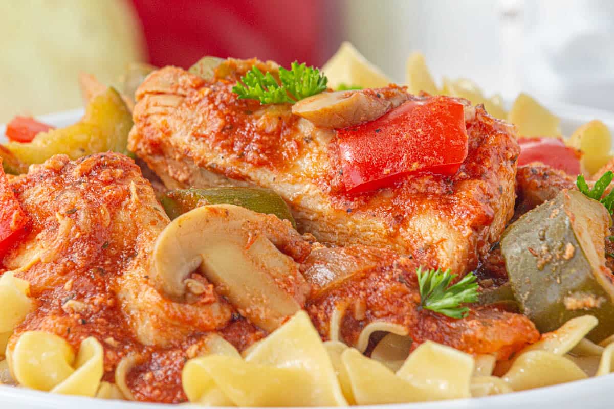 Chicken cacciatore over noodles in a bowl.