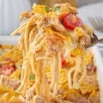 Gooey, cheesy queso chicken spaghetti in a dish. A serving is being scooped out.