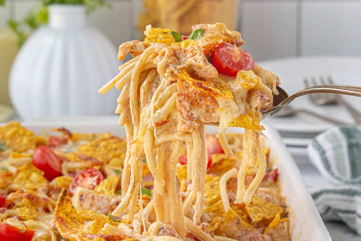 Cheesy Tex Mex queso pasta being scooped out of a casserole dish with a serving spoon.