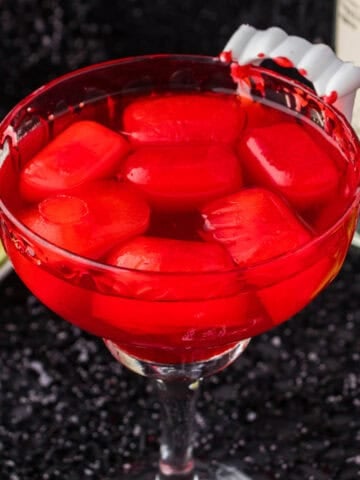 A vampire margarita in a cocktail glass, garnished with vampire teeth.