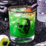 A green cocktail in a glass with a skull on it. This is a fun Halloween cocktail.