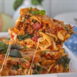 8 layer casserole being dished up out of a baking dish by a serving spoon.