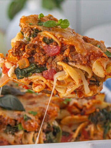 8 layer casserole being dished up out of a baking dish by a serving spoon.