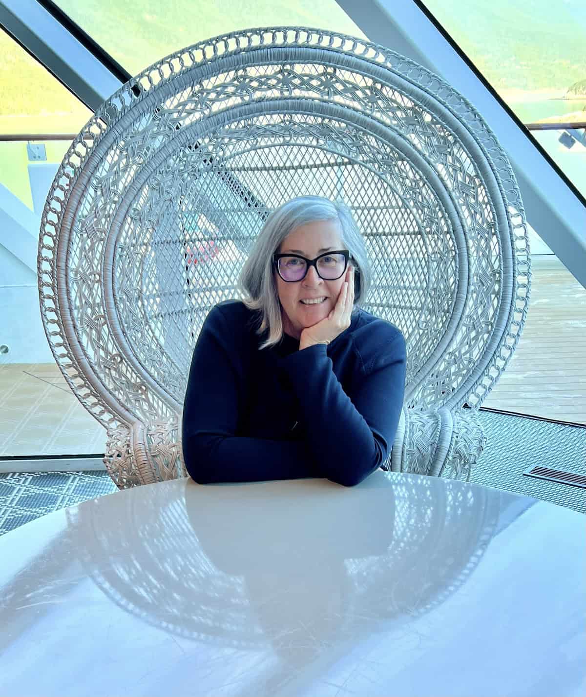 Blogger Deb Clark sitting in white chair in front of a table.