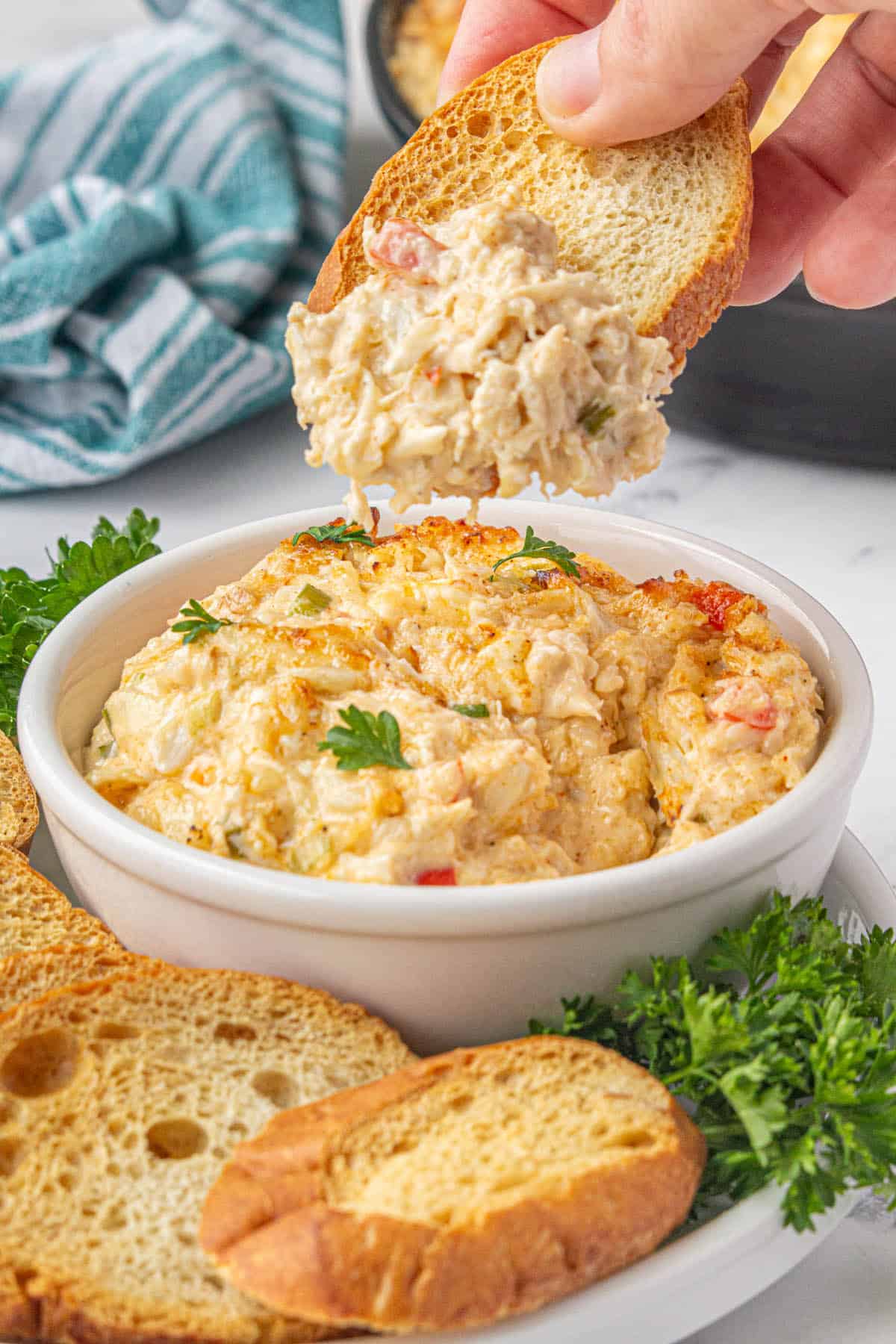 Hot Louisiana Crab Dip in a bowl surrounded by baguettes.