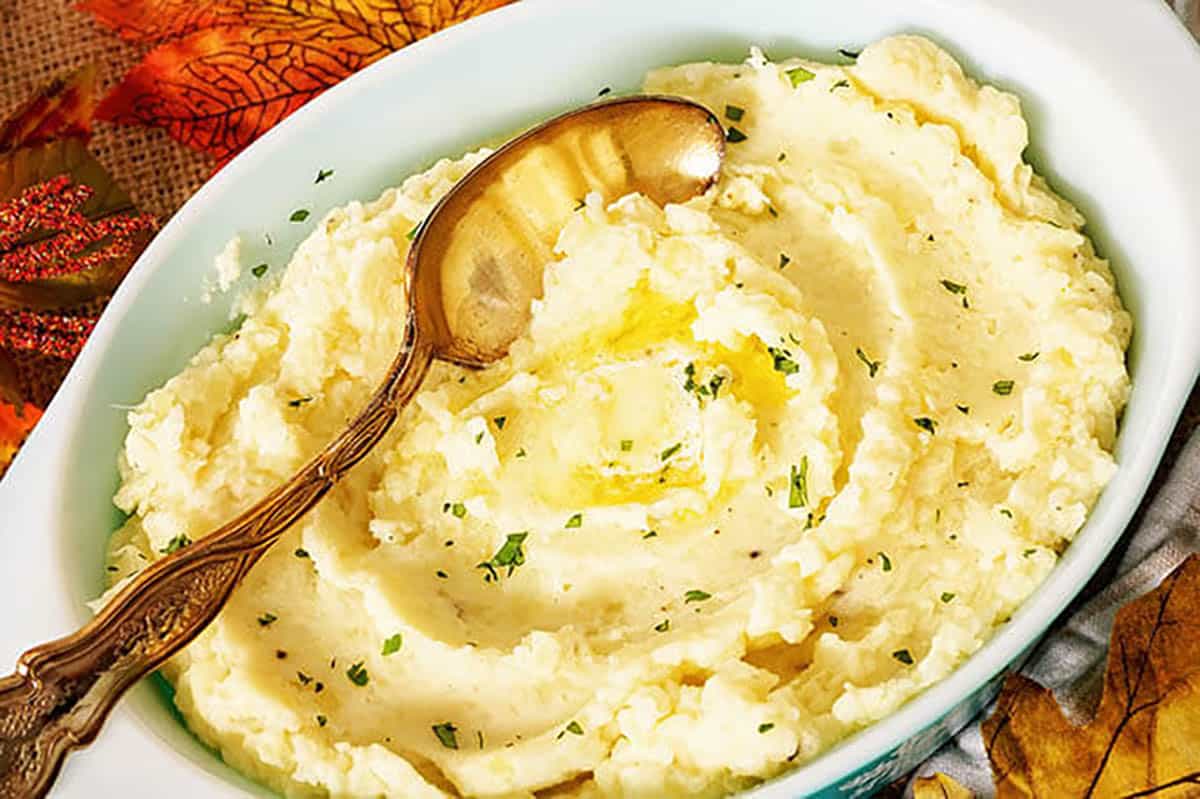 Mashed cauliflower and potatoes in a bowl with a serving spoon.