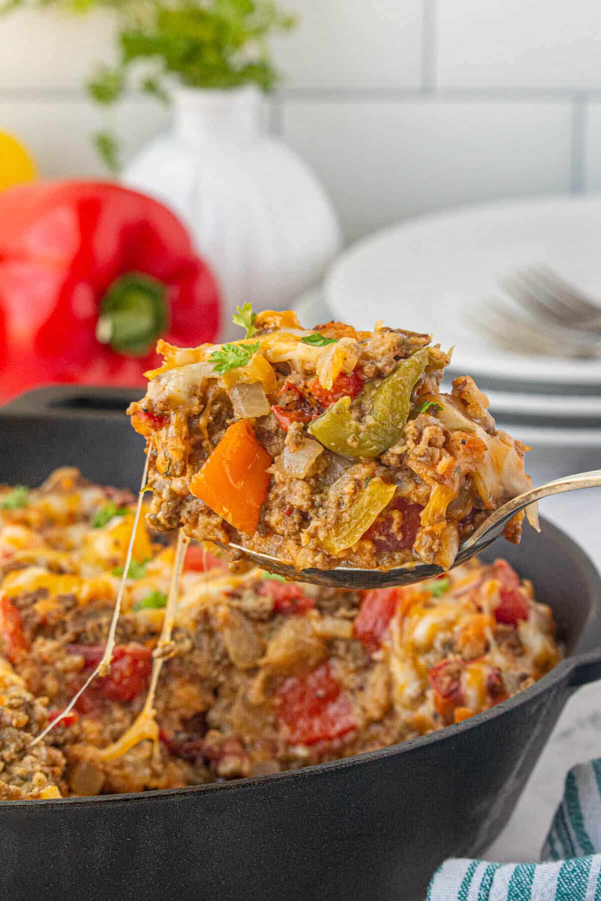 Stove top stuffed pepper casserole in a cast iron skillet. With a serving spoon taking a big scoop out of the casserole.