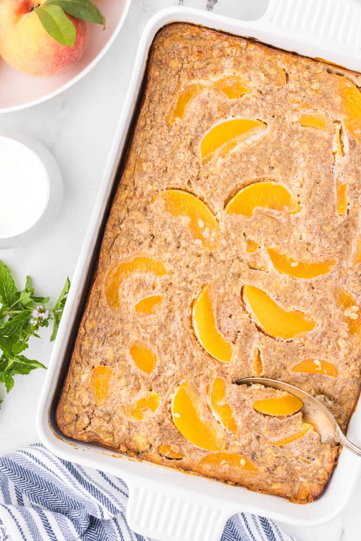 A casserole dish filled with Peaches and Cream Oatmeal Bake.