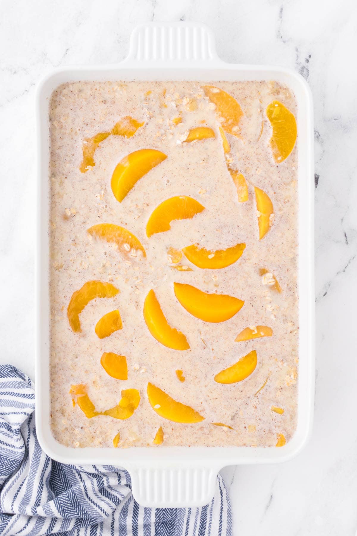 Oatmeal breakfast casserole in a white casserole dish, ready to go into the oven to be baked.