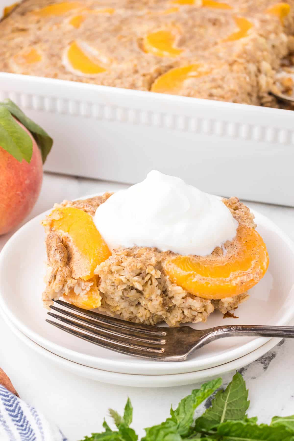 Peaches and Cream Oatmeal Bake, with a serving sitting on a plate with a fork.