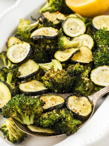 Roasted Zucchini and Broccoli on a platter with a serving spoon.