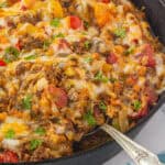 Stuffed pepper casserole in a pan with a serving spoon ready to scoop out a serving.