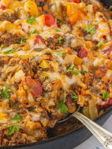 Stuffed pepper casserole in a pan with a serving spoon ready to scoop out a serving.