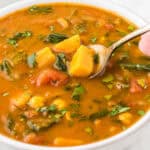 A bowl filled with vegetarian Gypsy Soup, with a spoon taking a big spoonful out.