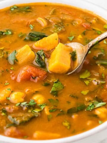 A bowl filled with vegetarian Gypsy Soup, with a spoon taking a big spoonful out.