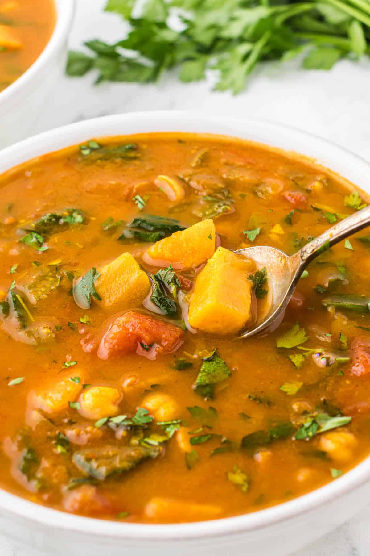 A bowl filled with sweet potato soup, with a spoon.