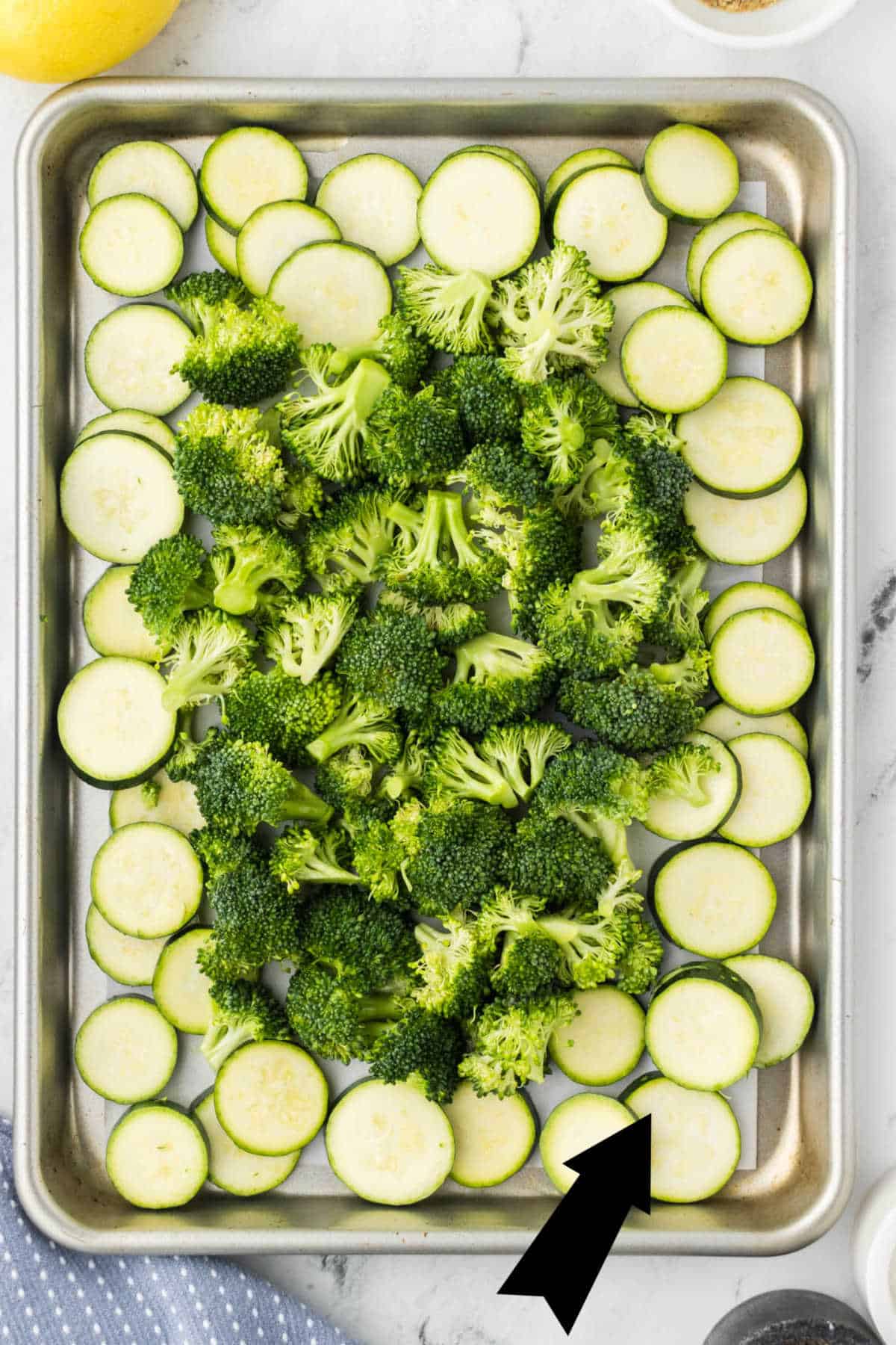 Zucchini and Broccoli on a sheet pan, with an arrow overlay indicating where to place the zucchini for roasting.