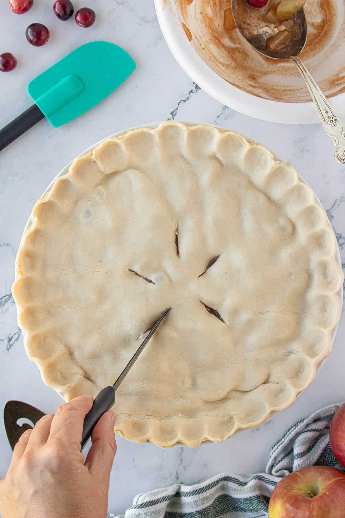 Vents being sliced into the top of the pie to allow steam to escape while baking.