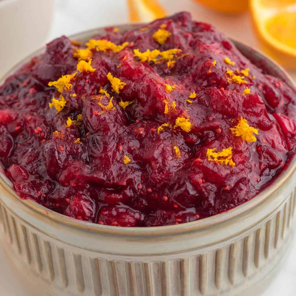 A tan serving bowl filled with cranberry apple orange sauce.