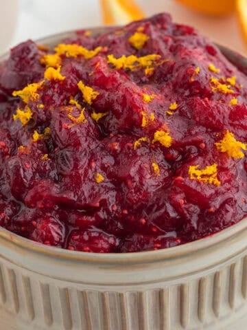 A tan serving bowl filled with cranberry apple orange sauce.