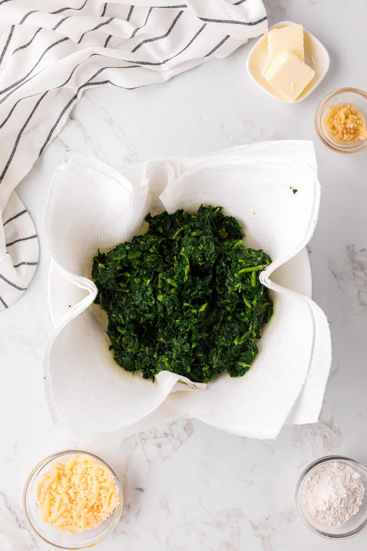 Cooked spinach draining over paper towels.