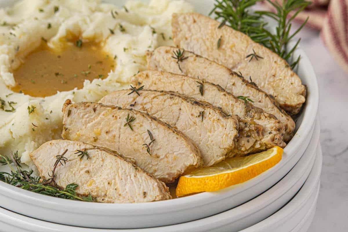 Sliced turkey on a plate with mashed potatoes and gravy.