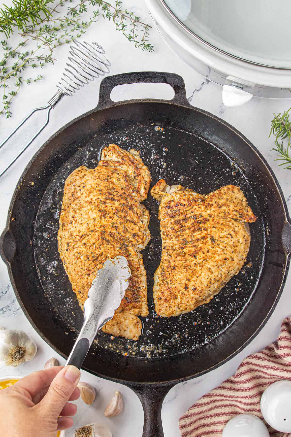 Turkey tenderloins being seared in a cast iron skillet.