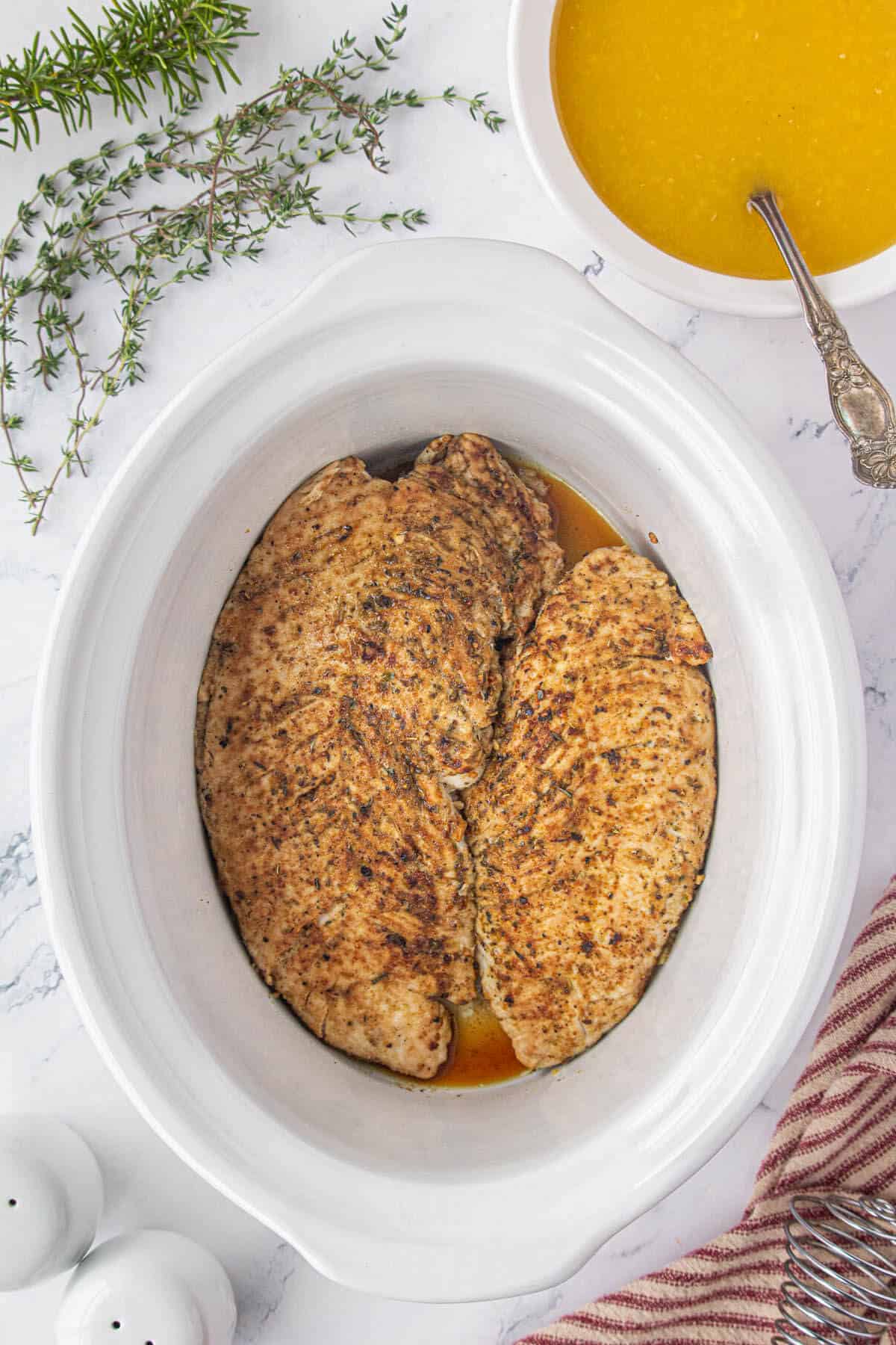 Turkey tenderloins in a white crockpot.