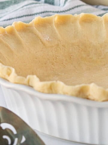 Unbaked pie crust in glass pie dish.