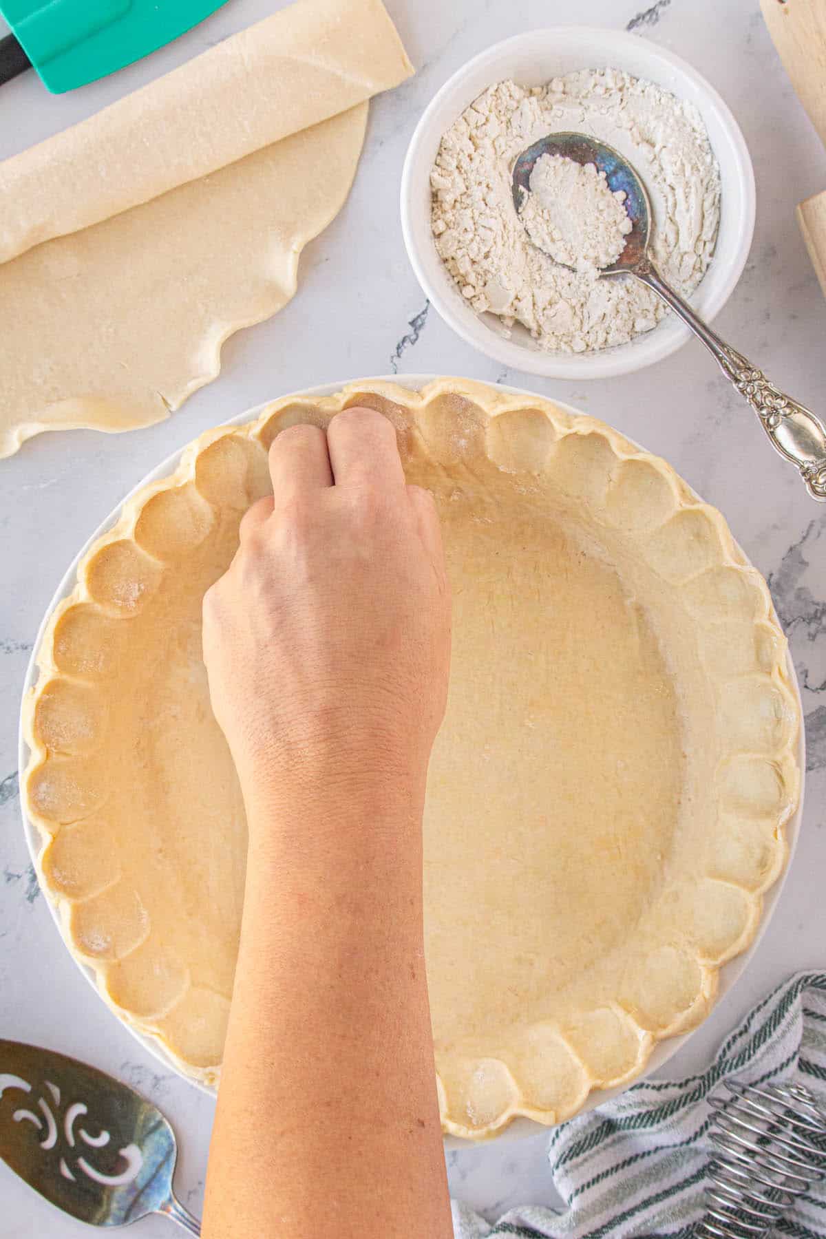 A hand flutting the edges of a pie crust.