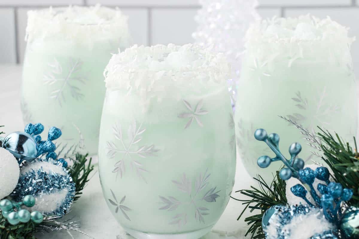 Three glasses filled with frosty blended cocktails garnished with shredded coconut flakes.