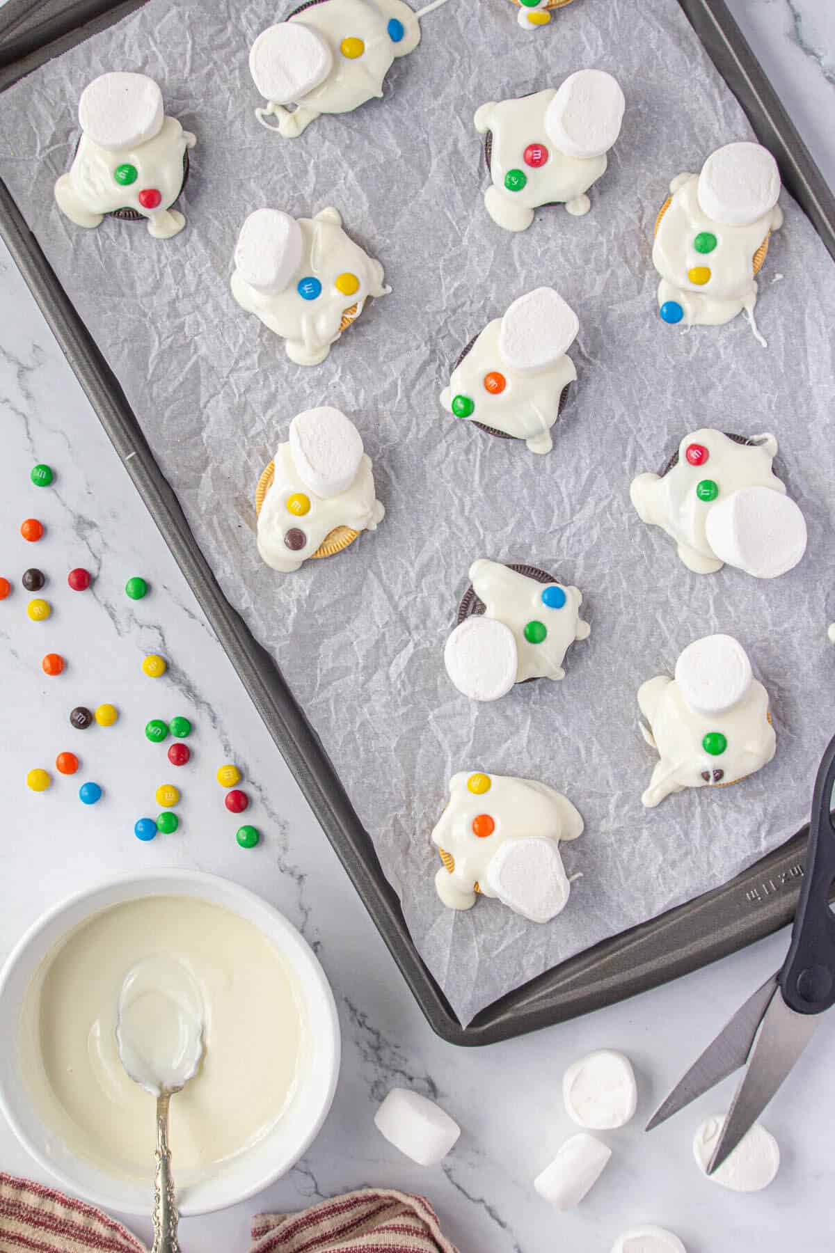 Mini m&m's placed on the melted chocolate for to simulate buttons on the melted snowman cookies.