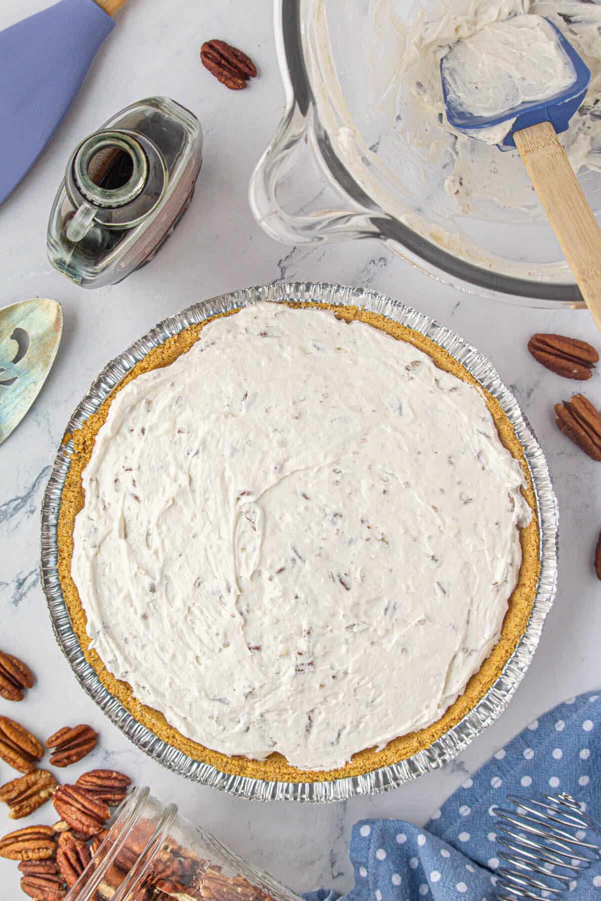 A graham cracker crust filled with pecan cream cheese pie mixture.