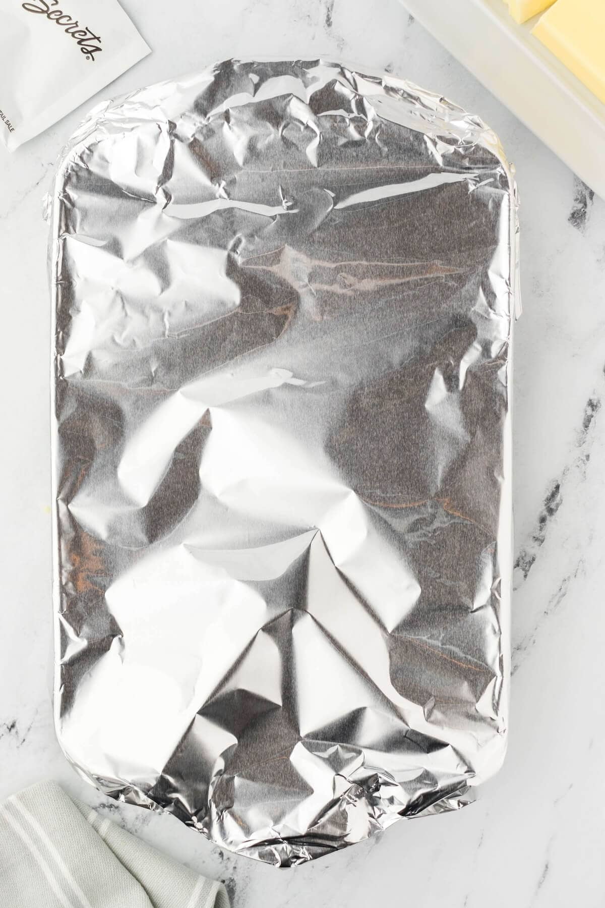 A casserole dish covered with aluminum foil, ready to put into the oven.