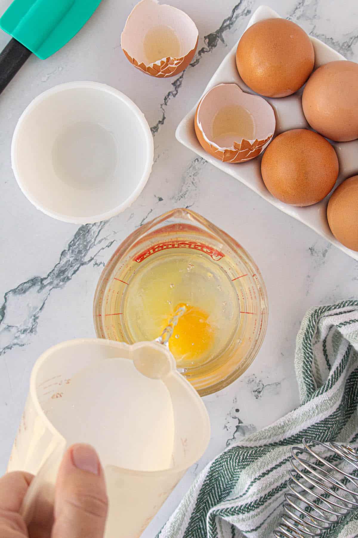 Water being poured into a measuring cup with an egg in it. 