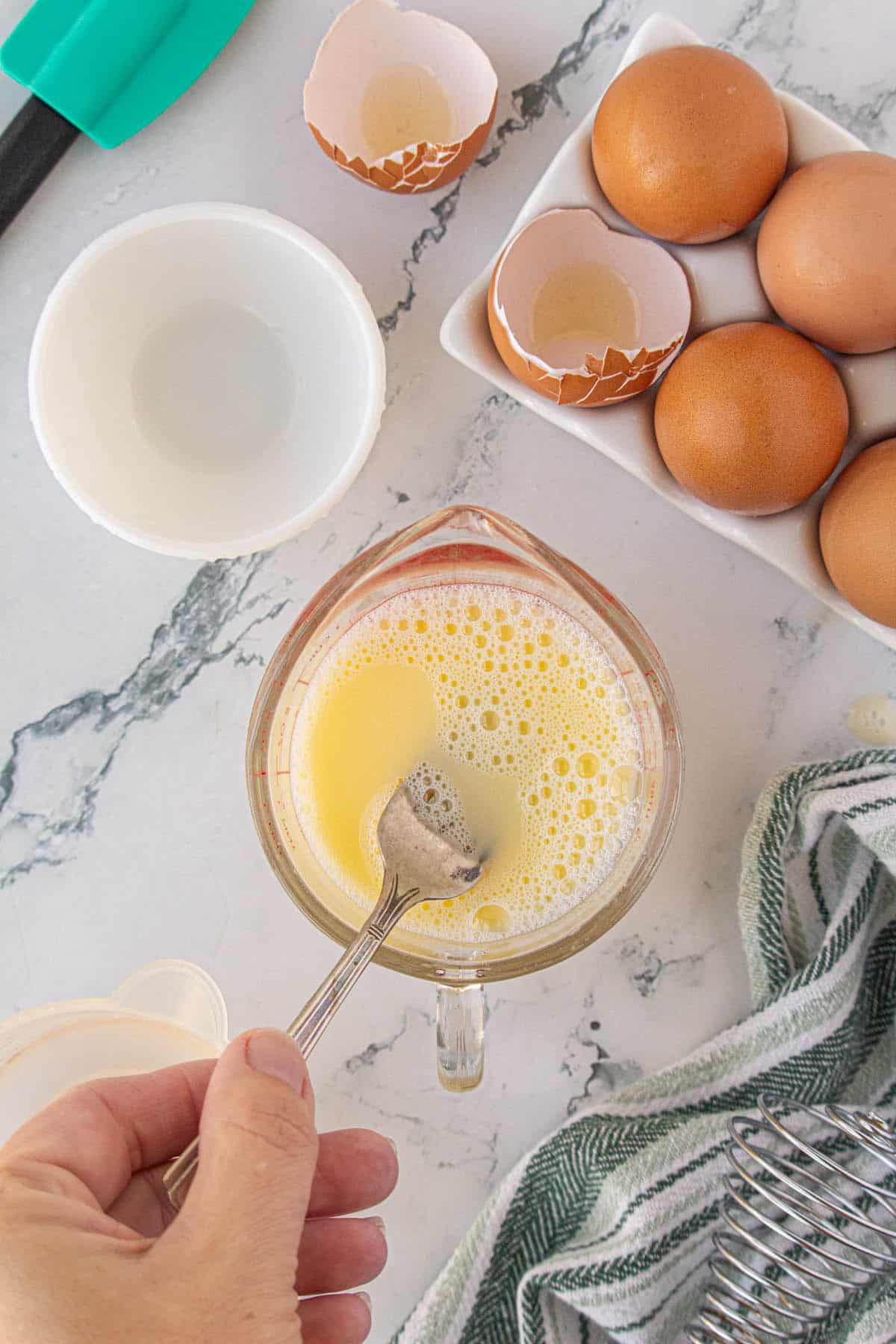 An egg water mixture being whisked in a measuring cup.