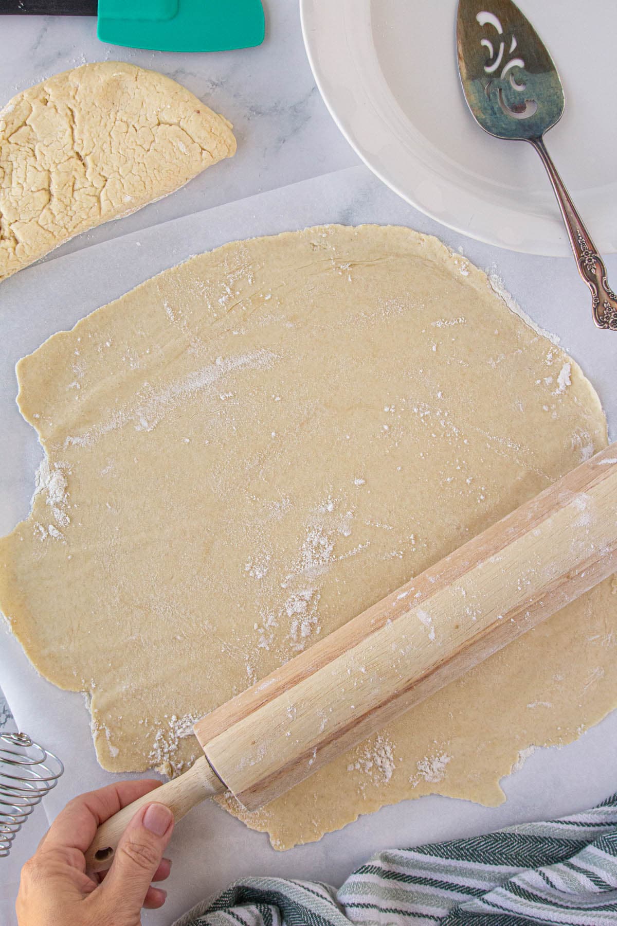 Pie crust being rolled out by a rolling pin.